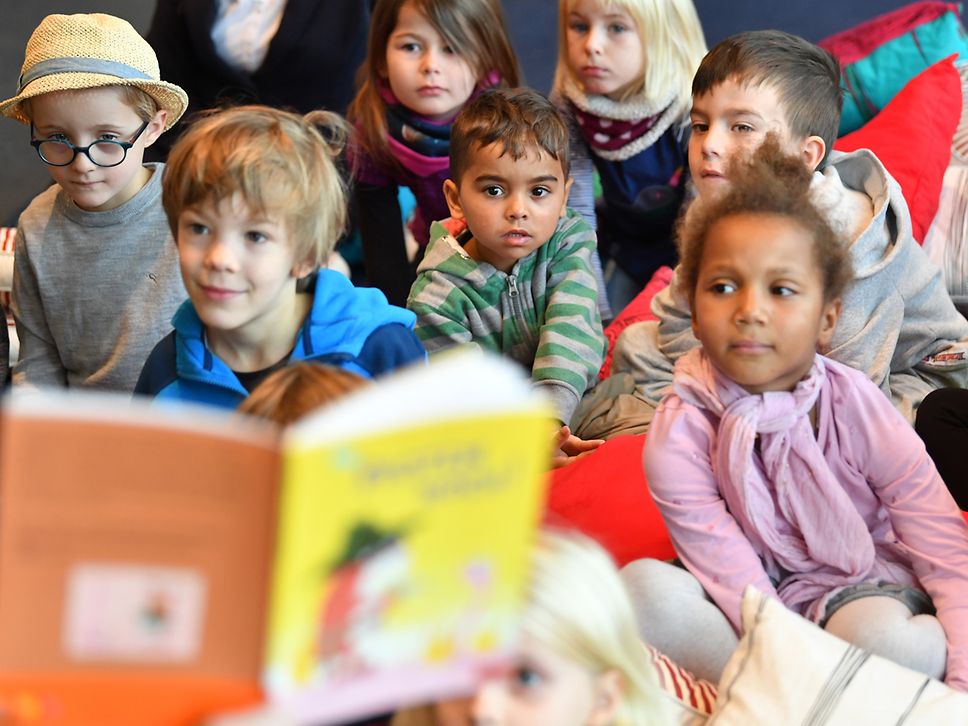 Gruppe von Kindern hören beim Vorlesen zu