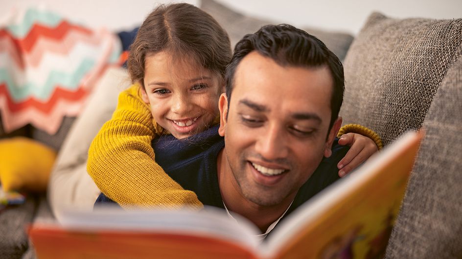 Mädchen und Vater lesen gemeinsam aus einem Buch