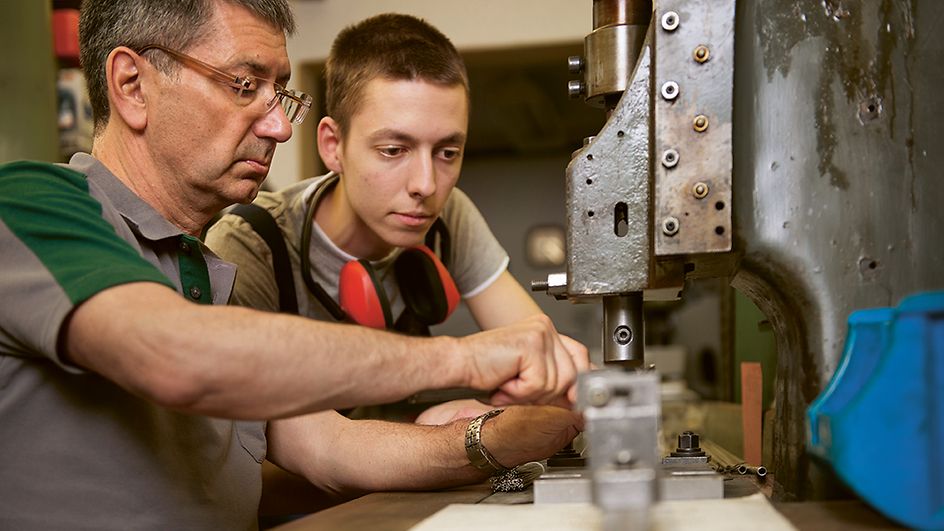 Handwerker und Azubi arbeiten in Werkstatt